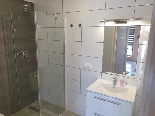 a bathroom with a shower and a sink and a mirror at Domki Przy Pogodnej in Ustronie Morskie