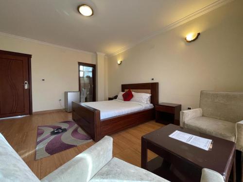 a bedroom with a bed and a couch and a table at Filimon Guest House in Addis Ababa