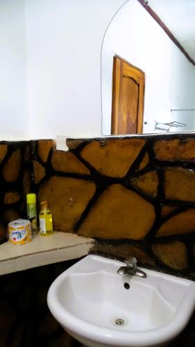 a bathroom with a sink and a stone wall at Home Feeling Neneu Lodge in Moshi