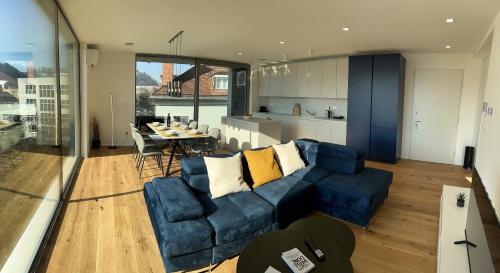 a living room with a blue couch and a kitchen at Garden Residence in Ljubljana
