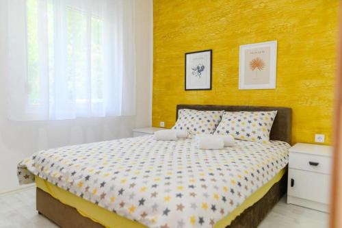 a bedroom with a large bed with a yellow wall at Sunflower Apartmani in Soko Banja