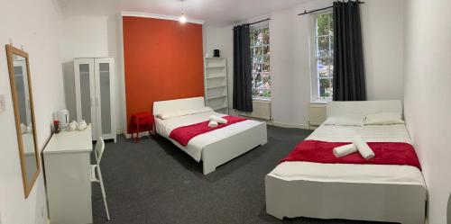 a bedroom with two beds and a red wall at WARREN STREET GUEST HOUSE in London