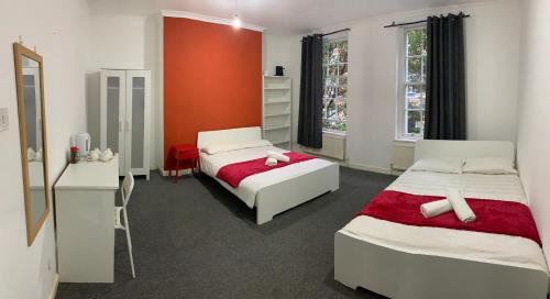 a bedroom with two beds and a red wall at WARREN STREET GUEST HOUSE in London