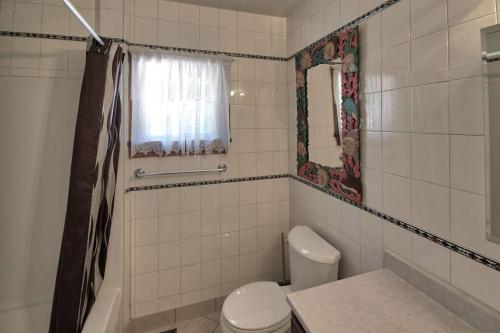 ein weißes Bad mit einem WC und einer Dusche in der Unterkunft Sunset Getaway, Cozy 5 people, 2 min to beach! in Lambton Shores