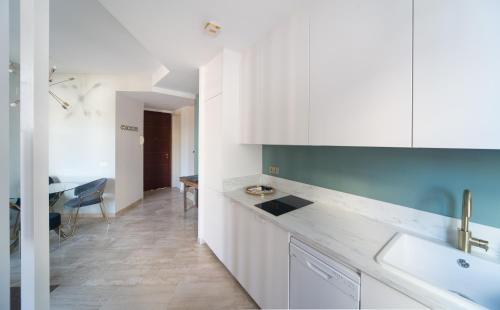 cocina con armarios blancos, fregadero y mesa en EXCLUSIVE TRIPLEX WITH PRIVATE TERRACE, en Sevilla