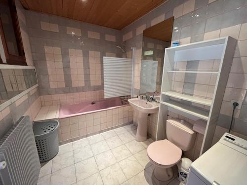 La salle de bains est pourvue d'une baignoire rose, de toilettes et d'un lavabo. dans l'établissement Maison bord de mer proche des Sables d'Olonne, à Talmont-Saint-Hilaire