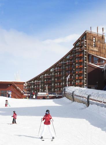 two people on skis in the snow in front of a building at Hôtel Club mmv Les Mélèzes **** in Arc 2000