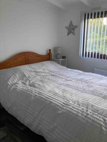 a bedroom with a bed with a striped comforter at 7F Cwtch Cymru Lodge, Caer Beris Holiday Park - no commercial vehicles permitted on site in Builth Wells