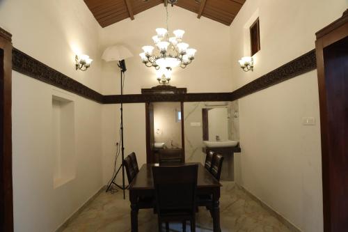 een eetkamer met een tafel en een kroonluchter bij Pear Tree Luxe Entire 3BHK Villa - Only For Family in Kotagiri