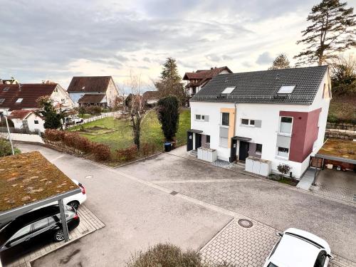 ein weißes Haus mit einem Auto, das in einer Einfahrt parkt in der Unterkunft Großes & Modernes Ferienhaus 2 Minuten von Meersburg Innenstadt in Meersburg
