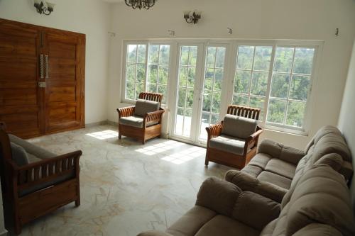 a living room with a couch and chairs and windows at Pear Tree Luxe Entire 3BHK Villa - Only For Family in Kotagiri