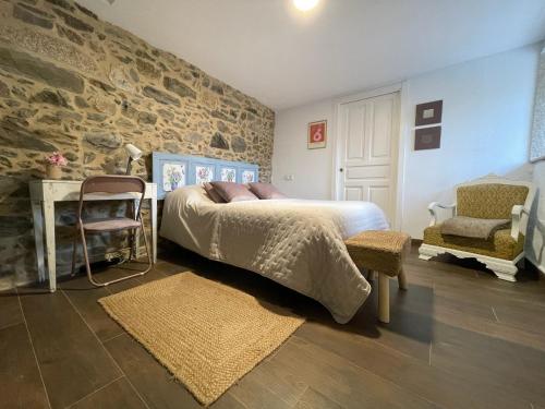 a bedroom with a bed and a stone wall at A Costa, Valle del Mendo in Oza dos Ríos