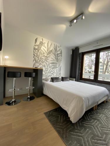 een slaapkamer met een groot wit bed en 2 bureaus bij Studios & chambres aux portes de Genève in Saint-Julien-en-Genevois