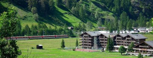 a train traveling past a resort with a mountain at 2.5 Zimmerwohnung für Sportler & Familien WHG 132 & WHG 612 in Täsch