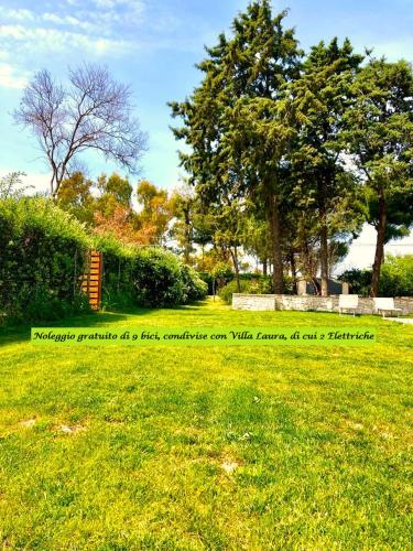 a sign in a field with trees and grass at Villa Costanza in Bari