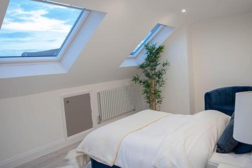 a white bedroom with a bed and two windows at Stylish Skylight Room in a Luxury House in Catford