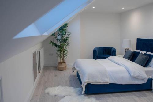 a bedroom with a bed and a blue chair at Stylish Skylight Room in a Luxury House in Catford