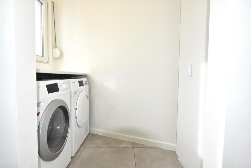 a white washing machine in a white laundry room at Cosy apartment Airport Brussels with terrace in Zaventem