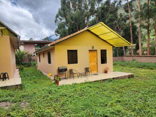 una pequeña casa amarilla con mesa y sillas en Casita Campestre Pitusiray, en Calca