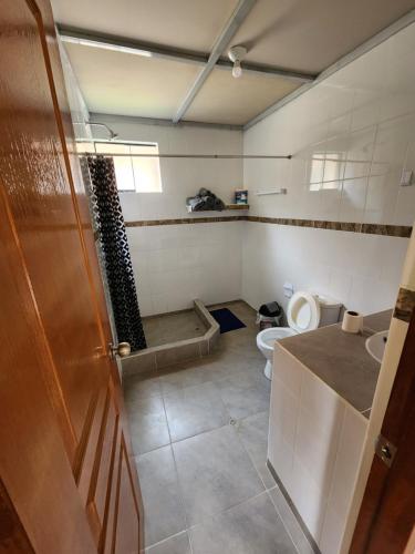 a bathroom with a toilet and a sink and a door at Casita Campestre Pitusiray in Calca