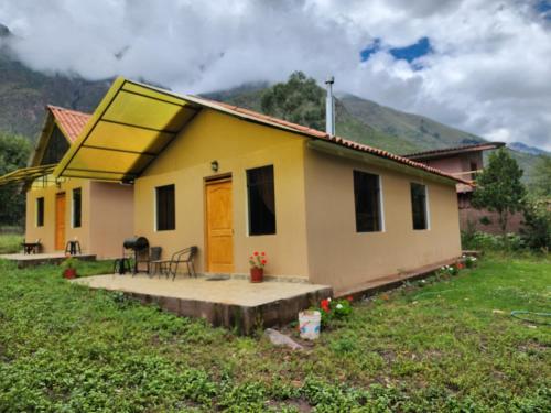a yellow house with a porch and a table at Casita Campestre Pitusiray in Calca