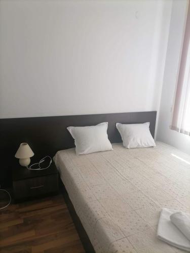 a bedroom with a bed with two pillows and a lamp at Sem.hotel -Afrikana in Sveti Vlas