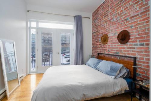 Un dormitorio con una pared de ladrillo y una cama en The Cozy Country Den en Quebec
