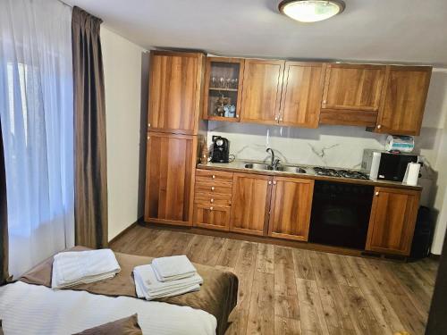 eine Küche mit Holzschränken und ein Bett in einem Zimmer in der Unterkunft Căsuța Adelina in Borşa
