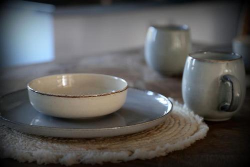 a bowl and a cup on a plate on a table at Gîte Au Moulin de Bougnon Calme et Dépaysement en Haute-Saône in Bougnon
