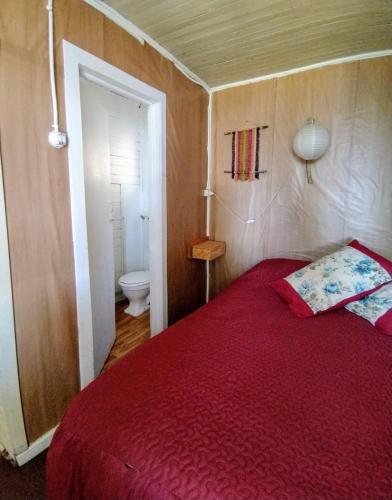 a bedroom with a red bed and a toilet at Hostal Casa Damasco in Ancud