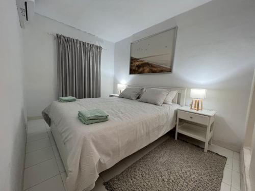 a white bedroom with a bed and a table with a night stand at Precioso Apartamento en Es Grau in Es Grau