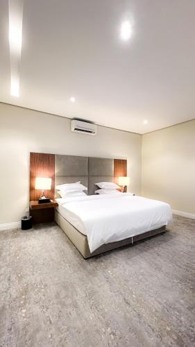 1 dormitorio con 1 cama blanca grande y 2 lámparas en شاليهات نفلة, en Ḩajlah