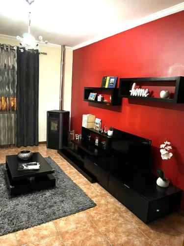 a living room with a red wall at Alojamento, Chelas Rural AL in Mirandela
