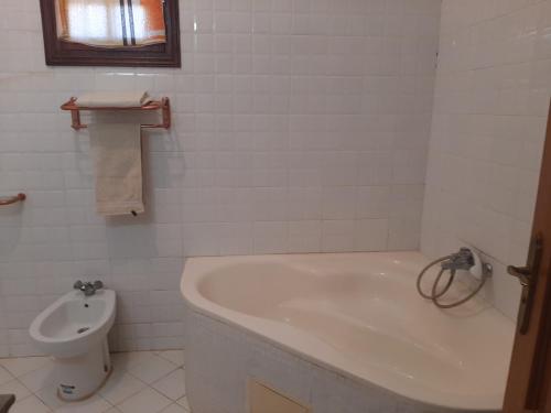 uma casa de banho branca com uma banheira e um WC em Maison á la campagne em El Guecheïne
