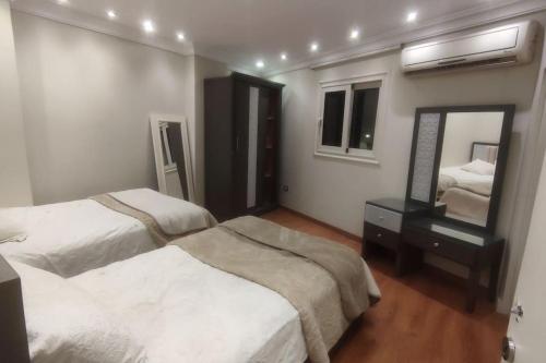 1 dormitorio con 2 camas y espejo en Comfortable softness en El Cairo
