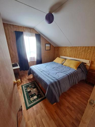 a bedroom with a bed with blue sheets and a window at Cabaña puerto varas in Llanquihue