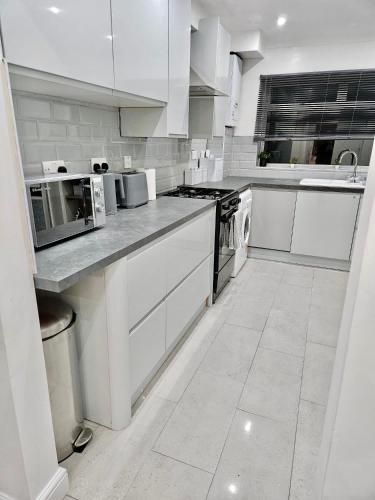a white kitchen with white cabinets and appliances at Cosy 3 bedroom Near Heathrow - 6 beds, sleeps 7, FREE PARKING in Staines upon Thames