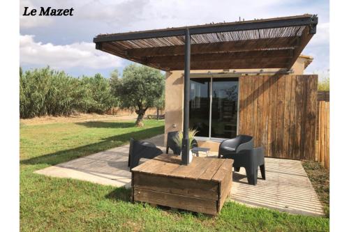 a pergola on a deck with a table and chairs at Manade de la clapiere-Mas du Plan in Le Cailar