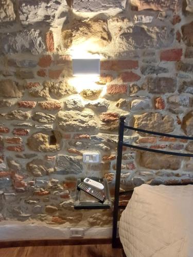 a room with a stone wall with a bed and a lamp at piccolo Garibaldi appartamento in Arezzo