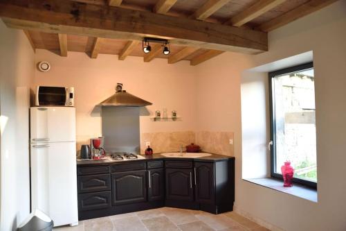 - une cuisine avec des armoires noires et un réfrigérateur blanc dans l'établissement Gîte à la ferme, au coeur du Mené, à Laurenan