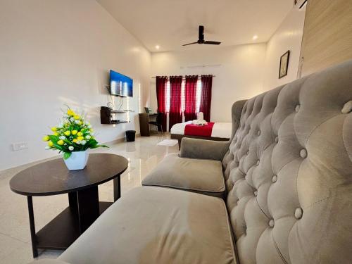 a living room with a couch and a table with flowers at Sai Shreyas Residency, Best Hotel near Bangalore Airport in Bengaluru