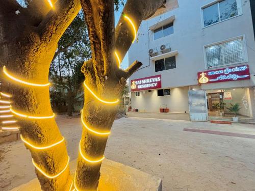 a tree with lights on it in front of a building at Sai Shreyas Residency, Best Hotel near Bangalore Airport in Bengaluru
