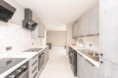 a white kitchen with a sink and a dishwasher at Stylish & modern studio in Burnley in Burnley