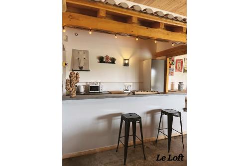 a kitchen with a counter and two stools at Manade de la clapiere-Mas du Plan in Le Cailar