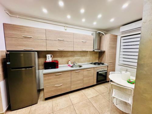 een keuken met houten kasten en een roestvrijstalen koelkast bij Confort City Residence in Popeşti-Leordeni