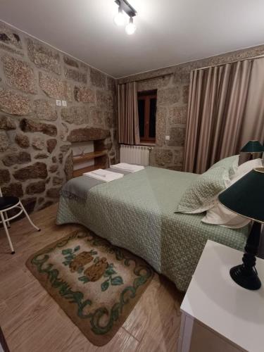 um quarto com uma cama e uma mesa com um candeeiro em Casa dos Avós em Avelal