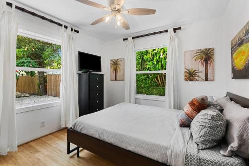 a bedroom with a bed with a ceiling fan and two windows at Perfect FLL Location with Putting Green in Fort Lauderdale