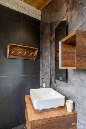 La salle de bains est pourvue d'un lavabo blanc et d'un mur en pierre. dans l'établissement Bodétour, tour charmante pour un séjour insolite, à Vimenet