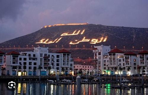 a mountain with a sign on it in front of buildings at Appartements à AGADIR 10min de la plage in Agadir