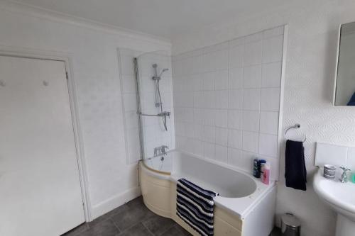 een witte badkamer met een bad en een wastafel bij Dog-friendly Gosport town house sleeps 8 in Brockhurst